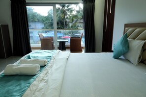 A hotel room with a bed, a table, chairs, and a view of the outside. - Prasanna Beach Resort - 150 meters to Kihim Beach (Alibag)