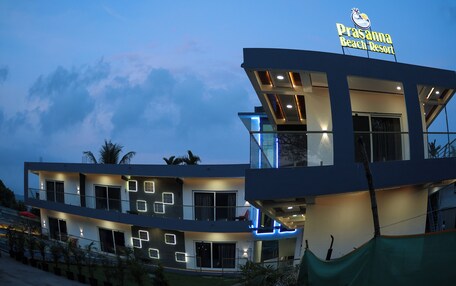 A modern multi-story building with a sign reading "Prasanna Beach Resort."
