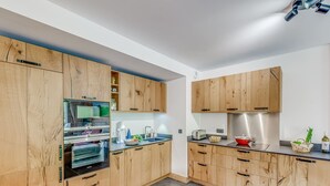 A modern kitchen with wooden cabinets, a built-in oven, and a stainless steel range hood. - Family apartment 8 pers, balcony, parking, wifi included (Champagny-en-Vanoise)