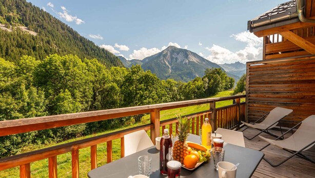 A wooden deck with a table set for two, overlooking a mountainous landscape. - Family apartment 8 pers, balcony, parking, wifi included (Champagny-en-Vanoise)
