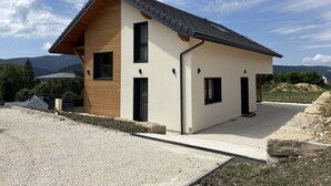 Ein modernes, zweistöckiges Haus mit geneigtem Dach, großen Fenstern und einer Schotterauffahrt.