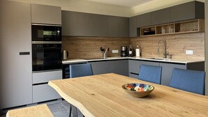 Eine moderne Küche mit grauen Schränken, einer Holz Arbeitsplatte und einem Esstisch mit blauen Stühlen.