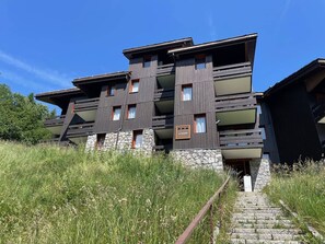 A modern multi-story building with a stone base and wooden upper floors.
