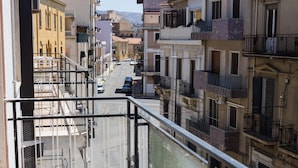 Une rue étroite, bordée de bâtiments des deux côtés, avec des balcons et un ciel dégagé.