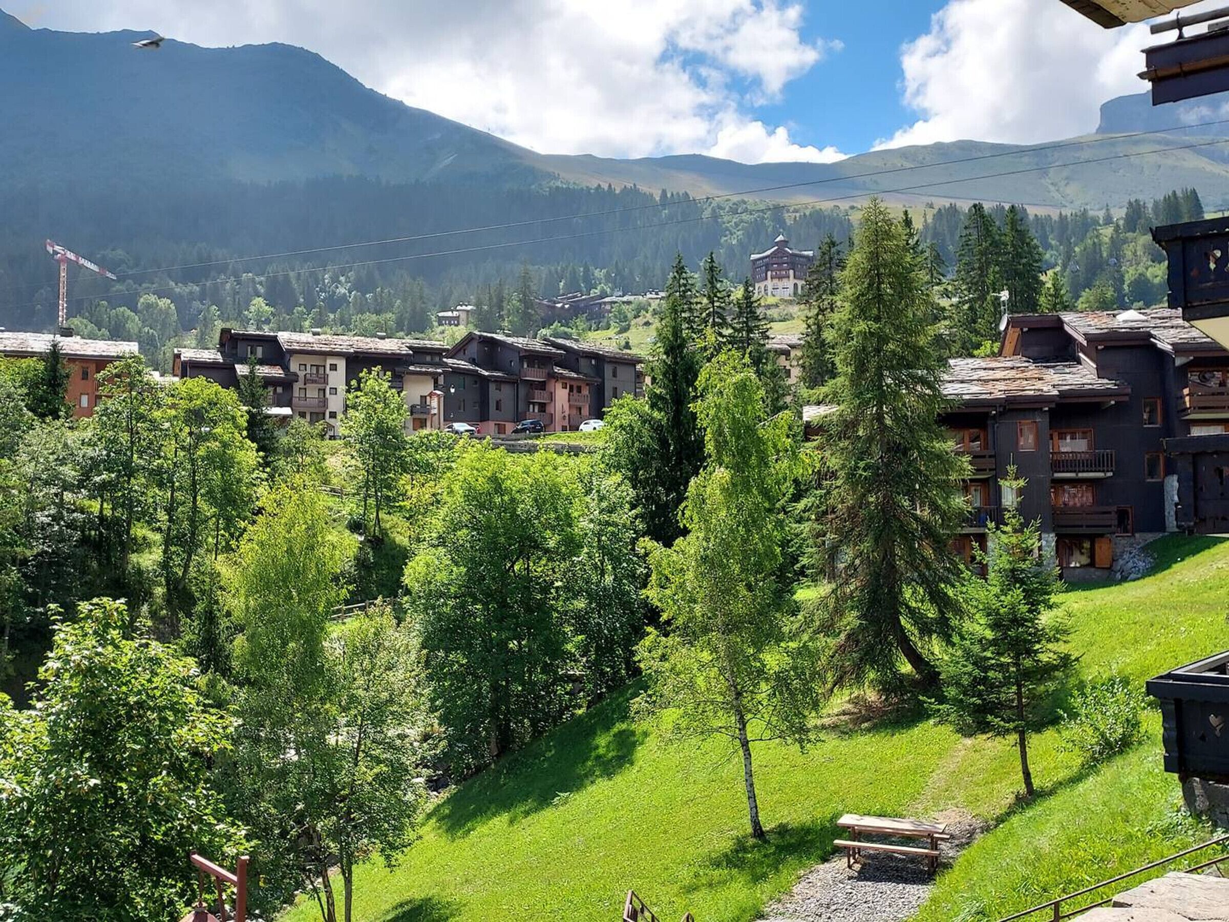A mountain village with traditional wooden buildings, a clear sky, and a view of distant mountains.