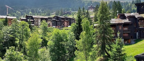Un village de montagne aux maisons traditionnelles en bois, avec un ciel dégagé et une vue sur les montagnes lointaines.