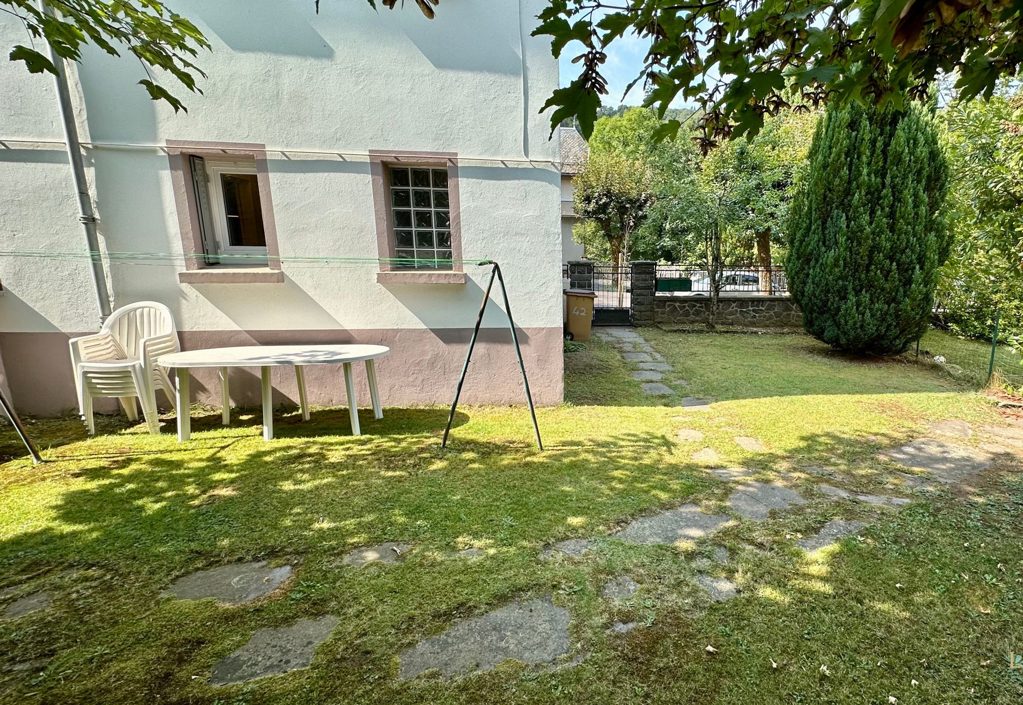 A courtyard with a white building, a stone pathway, and a small table with chairs.