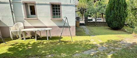 A courtyard with a white building, a stone pathway, and a small table with chairs.