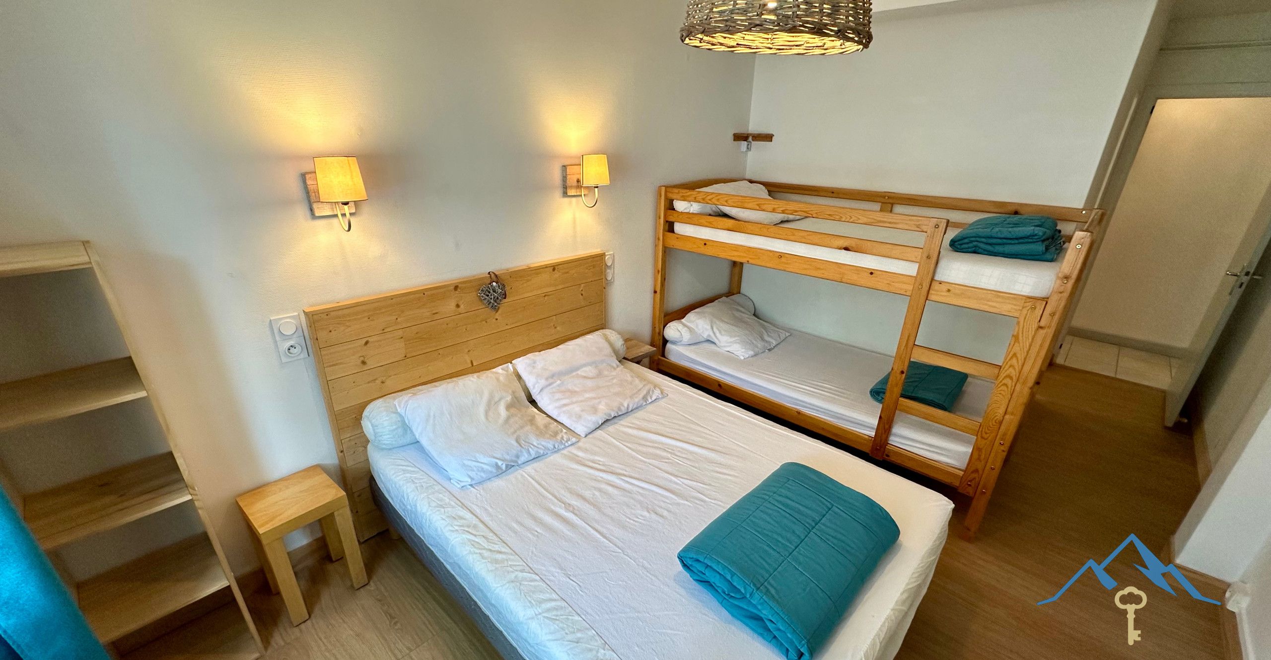 Ein Schlafzimmer mit Etagenbett, einem Holzkopfteil, einem Nachttisch und zwei Wandleuchten.