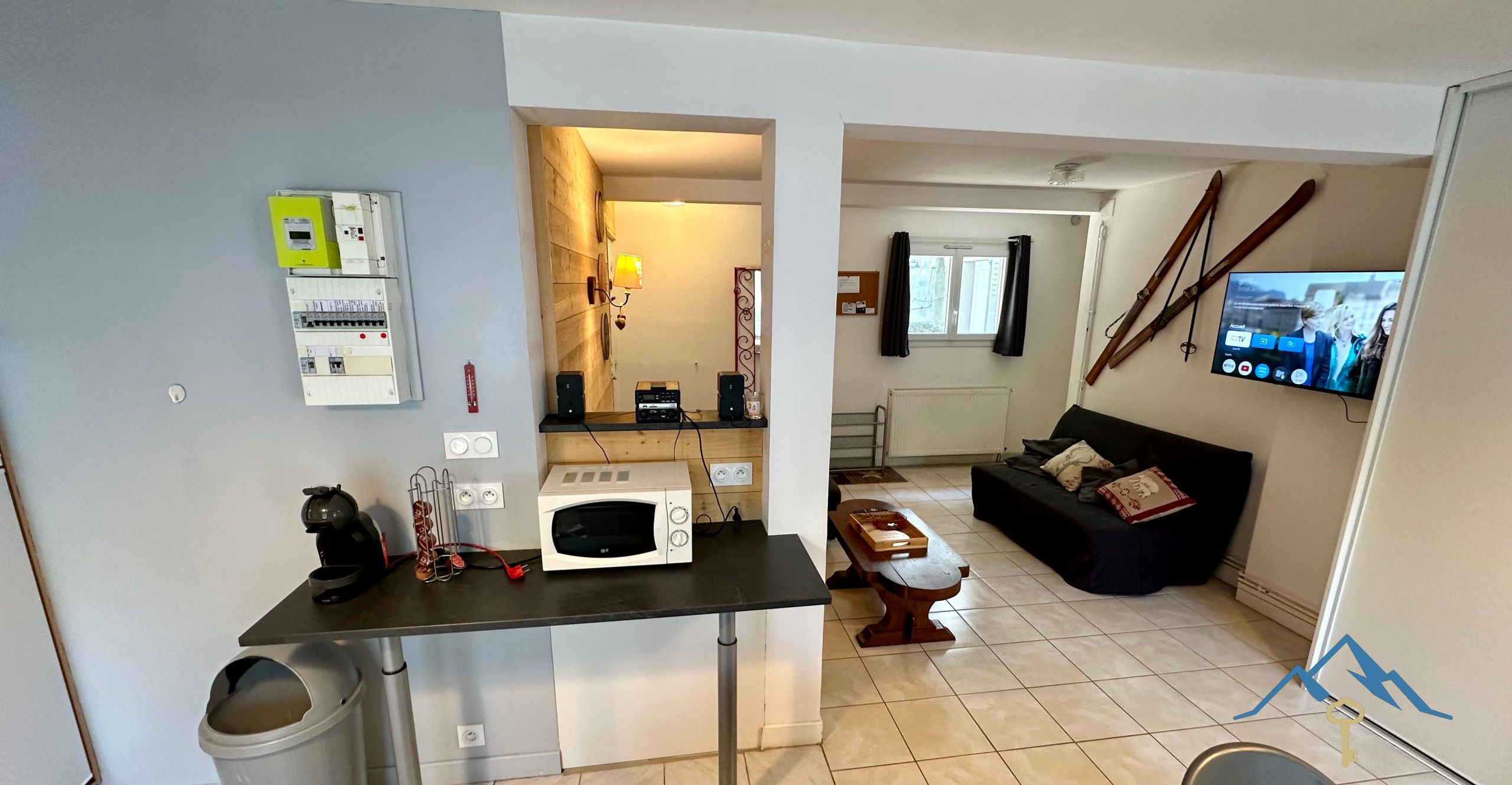 A compact living space with a kitchenette, a dining area, and a seating area with a TV.