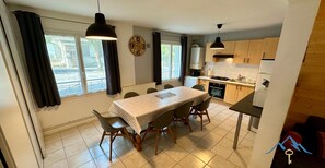 Una cocina moderna con armarios de madera, una mesa de comedor con sillas y un ventanal con cortinas.