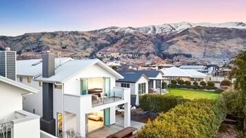 Ein modernes Wohngebiet mit Häusern, die Balkone, eine Terrasse und einen Blick auf schneebedeckte Berge bieten.