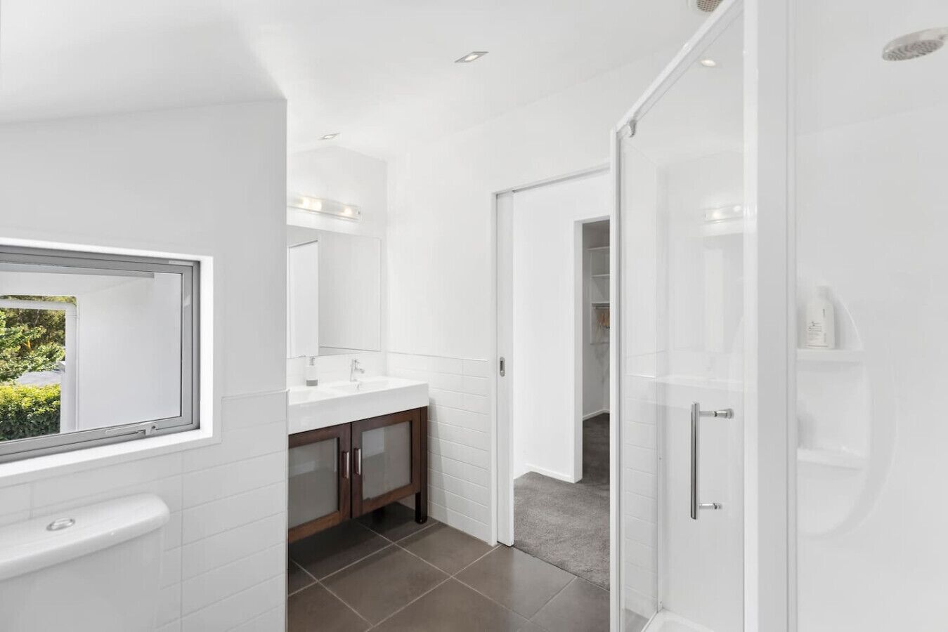 A modern bathroom with a large mirror, a white sink, and a shower area.