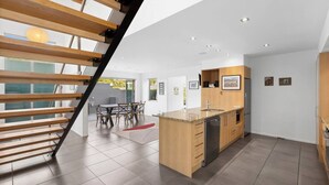 Une cuisine moderne dotée d’un îlot central en bois, d’appareils électroménagers intégrés et d’un coin repas avec une table et des chaises.