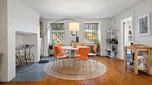 Une cuisine spacieuse avec une table de salle à manger ronde, des chaises orange et une grande fenêtre.