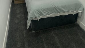 Un dormitorio pequeño y ordenado con una cama individual, una mesita de noche, una lámpara y una ventana con persianas.