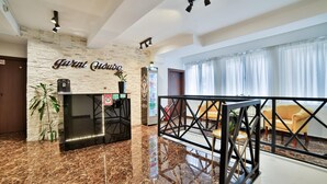 A modern lobby with a stone wall, a coffee machine, and a sign that reads "Jarnil Odore." - Garni House 46 Plus (Belgrade)