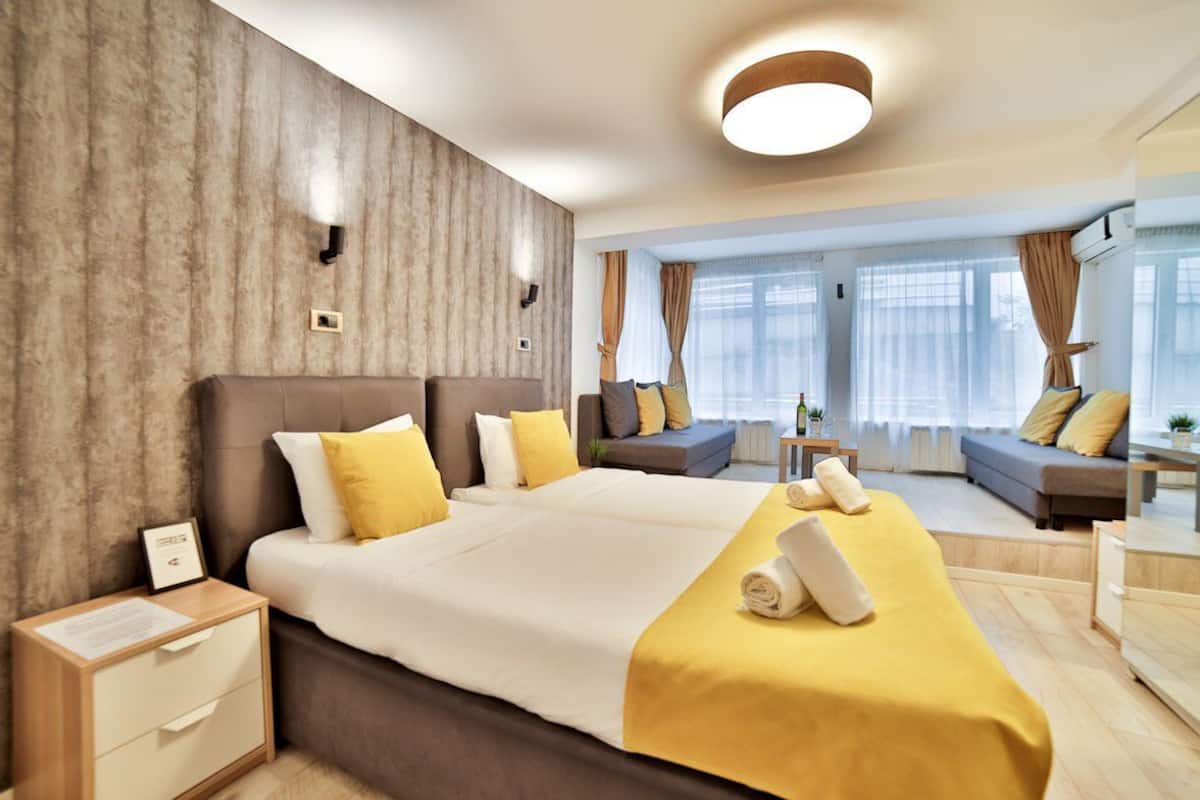 A modern hotel room with a large bed, a sofa, and a small table.