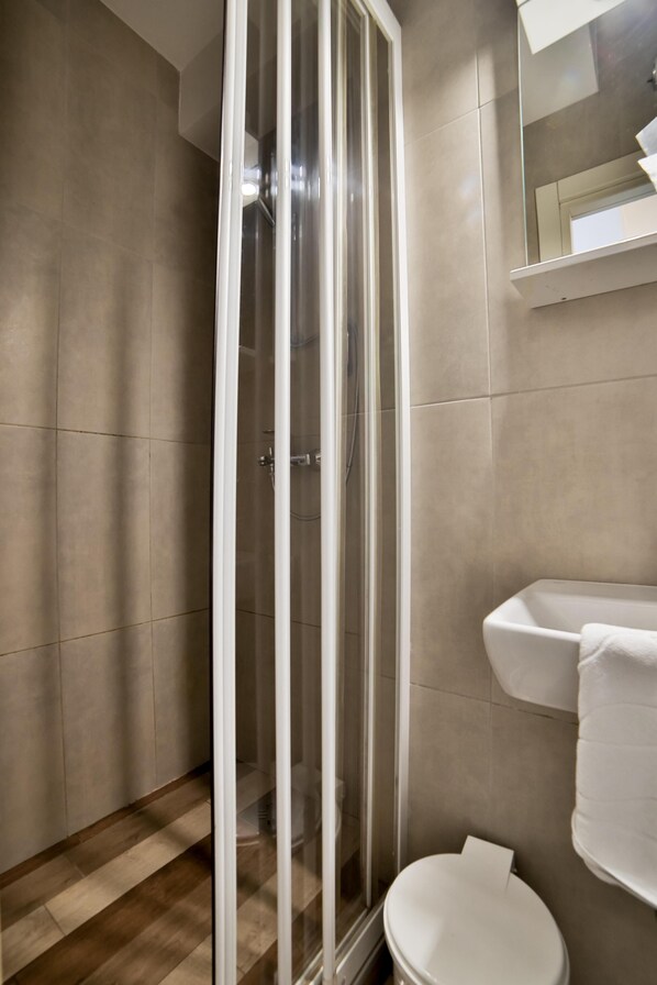Un baño con cabina de ducha, inodoro y lavamanos.