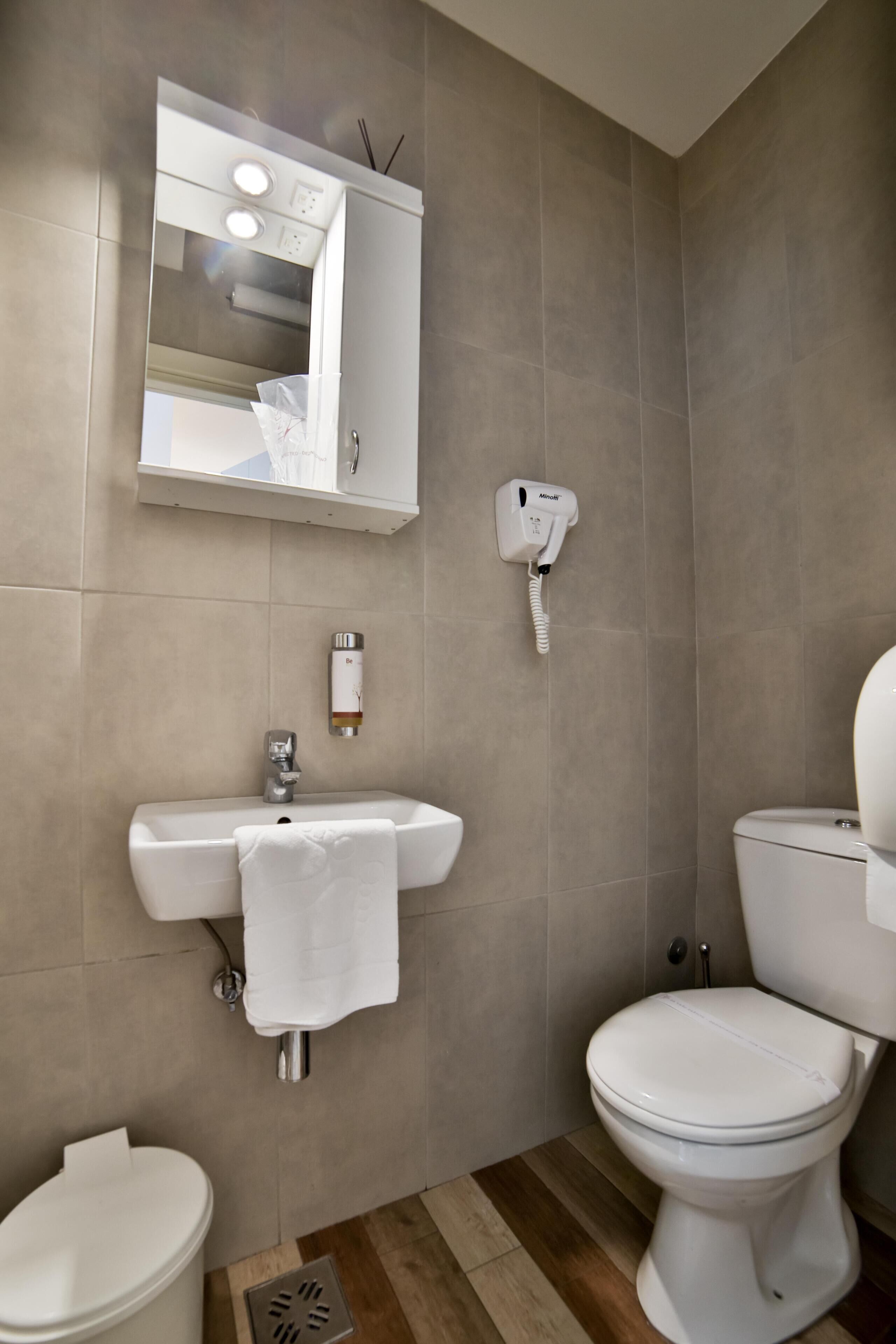 A modern bathroom with a white sink, toilet, and mirror.