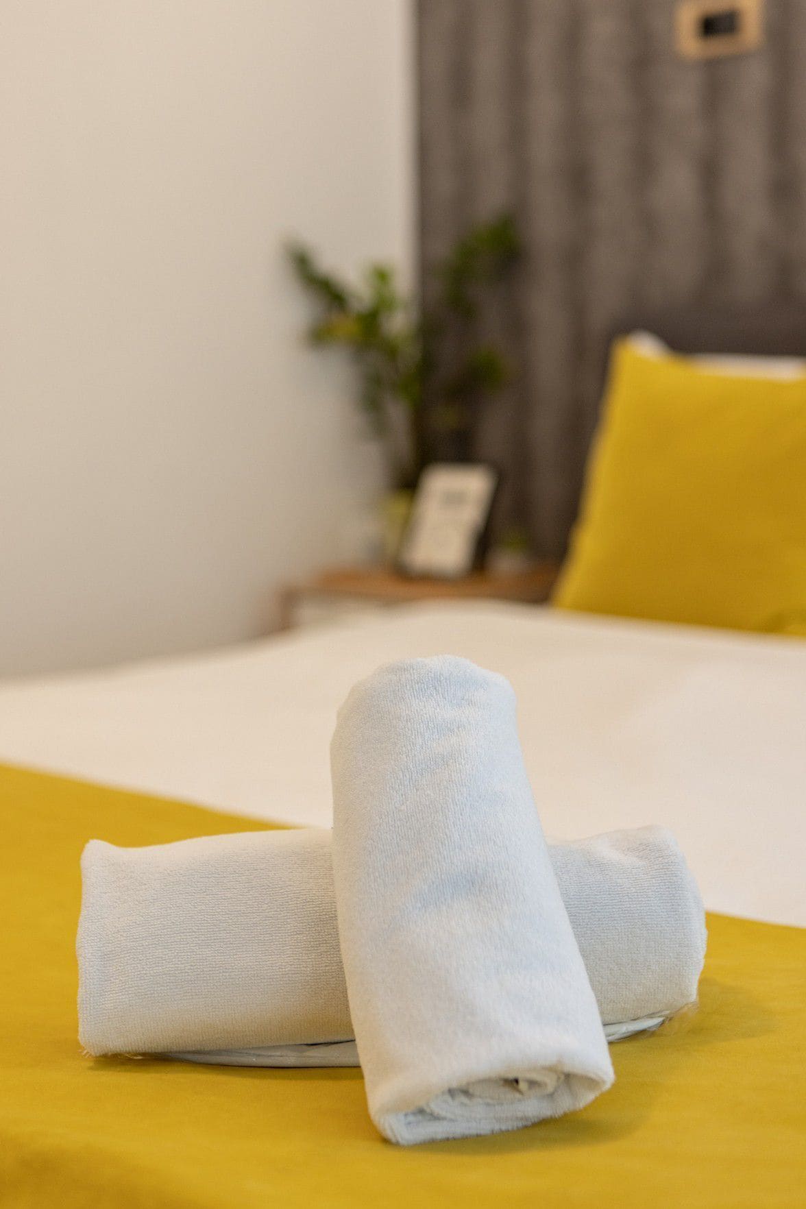Una cama bien hecha con sábanas blancas y una almohada amarilla.