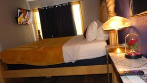 A hotel room with a bed, a bedside lamp, a television, and a decorative item on the nightstand.