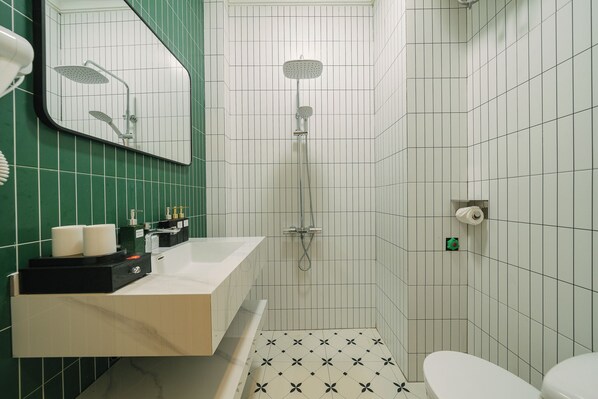 Un baño con ducha, inodoro y lavabo con artículos de aseo.