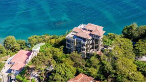 A multi-story building with balconies overlooking a clear blue sea, surrounded by lush greenery. - Elegant 3BR Oceanview Condo with Pool, Gym & Shuttle to Flamingo Beach (Playa Flamingo)