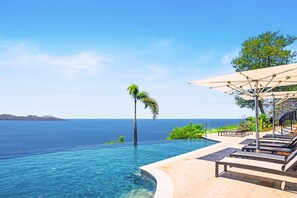 An infinity pool with a clear view of the ocean and a palm tree. - Elegant 3BR Oceanview Condo with Pool, Gym & Shuttle to Flamingo Beach (Playa Flamingo)
