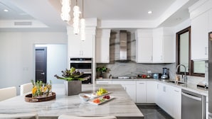 A modern kitchen with white cabinetry, a marble countertop, and a central island with seating. - Elegant 3BR Oceanview Condo with Pool, Gym & Shuttle to Flamingo Beach (Playa Flamingo)