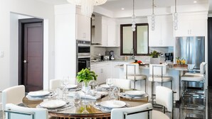 A modern kitchen with white cabinets, stainless steel appliances, and a central island with bar seating. - Elegant 3BR Oceanview Condo with Pool, Gym & Shuttle to Flamingo Beach (Playa Flamingo)