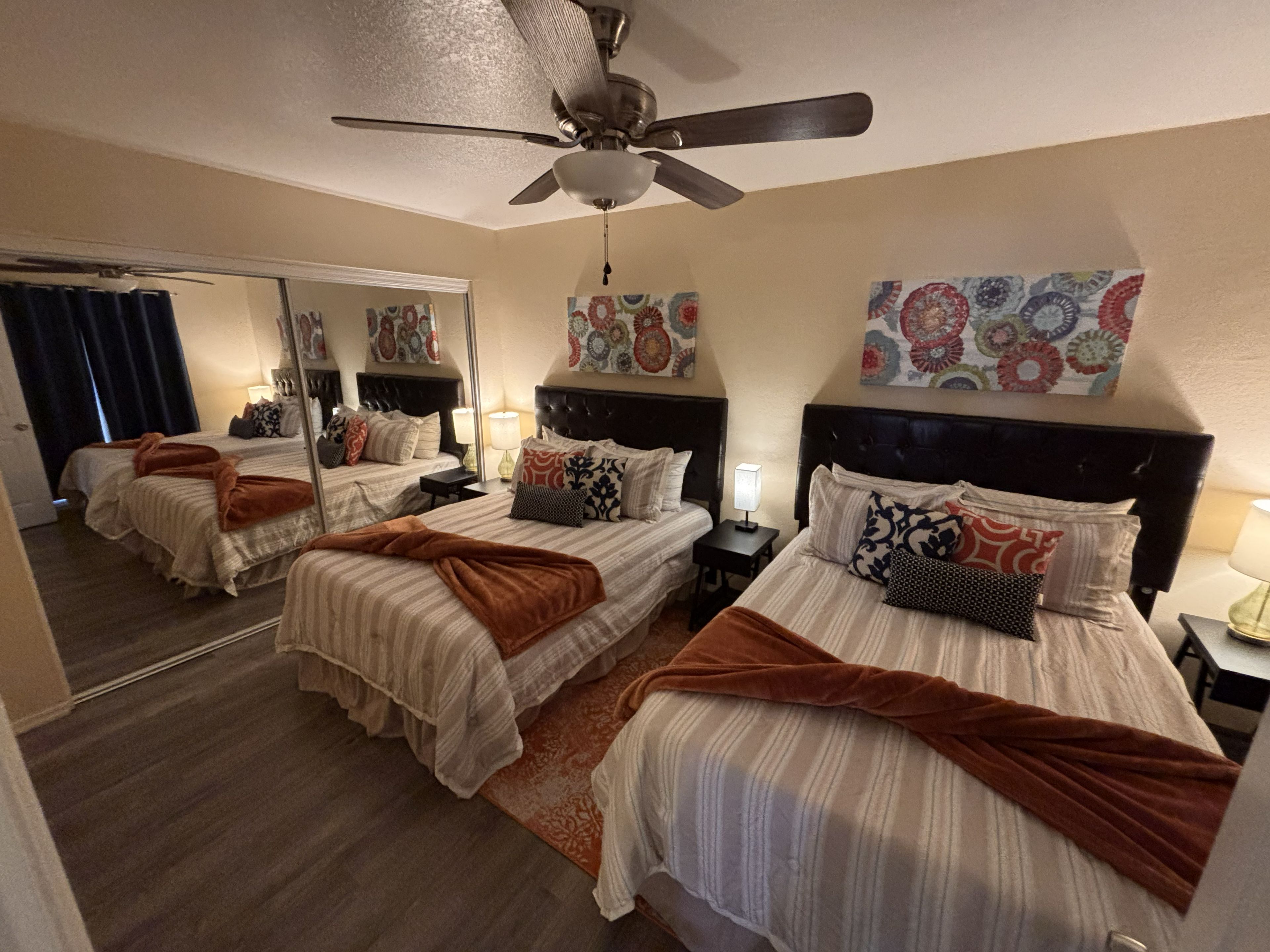 A hotel room with two beds, a ceiling fan, and decorative wall art.