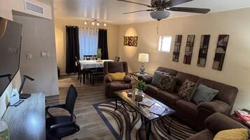 A modern living room with a sofa, coffee table, and a dining area in the background.
