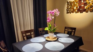Een eettafel met een donkere tafelkleed, witte placemats en een orchidee als decoratie.