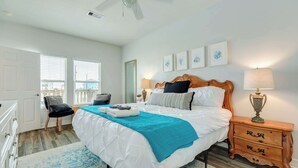 A bedroom with a bed, a nightstand, a chair, a ceiling fan, and a window with blinds. - Purple Paradise- Beachy Fun, Bay & Beach Views! (Surfside Beach)