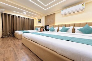 A hotel room with two beds, a large window with curtains, an air conditioning unit, and a wooden floor. - Hotel Anantshree Inn Shree Mahakaleshwar Temple Ujjain (Ujjain)