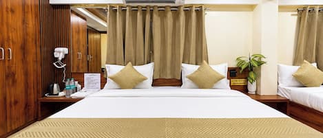 A hotel room with a large bed, two bedside tables, a mirror, a wall-mounted air conditioner, and a room service sign.