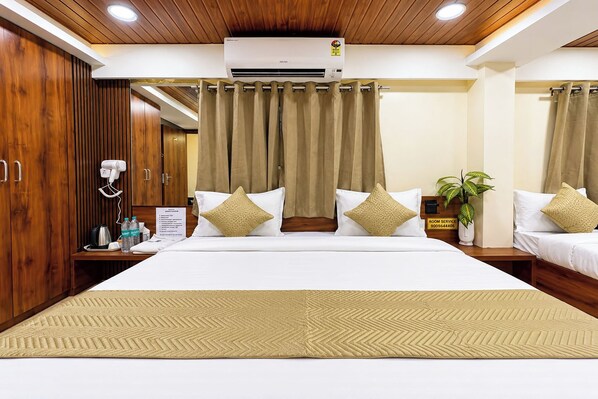 Habitación de hotel con una cama grande, dos mesitas de noche, un espejo, aire acondicionado de pared y un cartel de servicio de habitaciones.