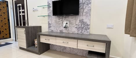 A modern bathroom with a vanity, a mounted TV, and a clock on the wall.