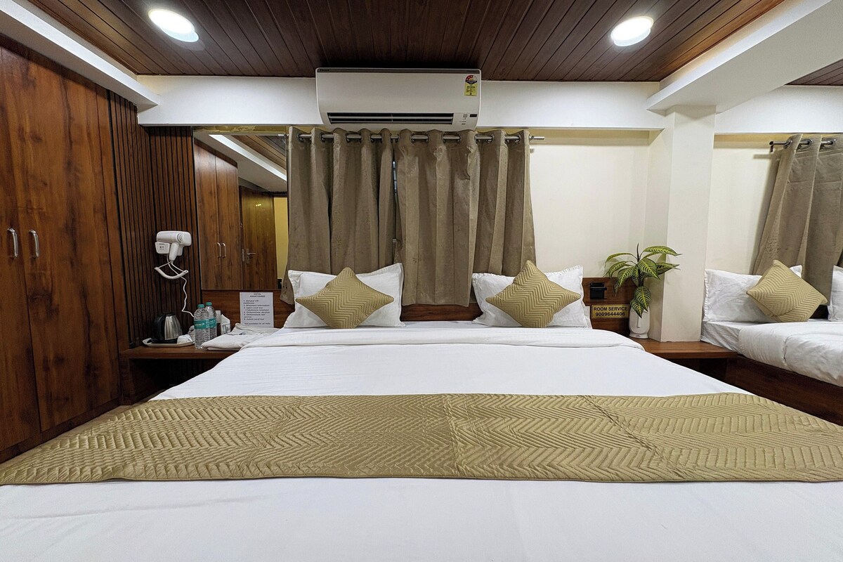 A hotel room with a large bed, two bedside tables, a wardrobe, and a bathroom visible through a curtain.