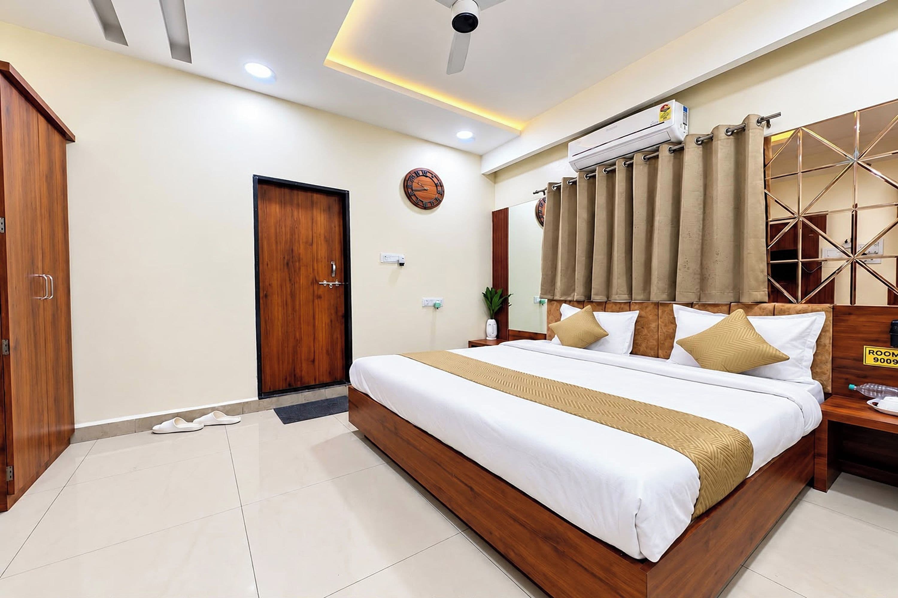 Habitación de hotel con una cama grande, un armario de madera y un ventilador de techo.