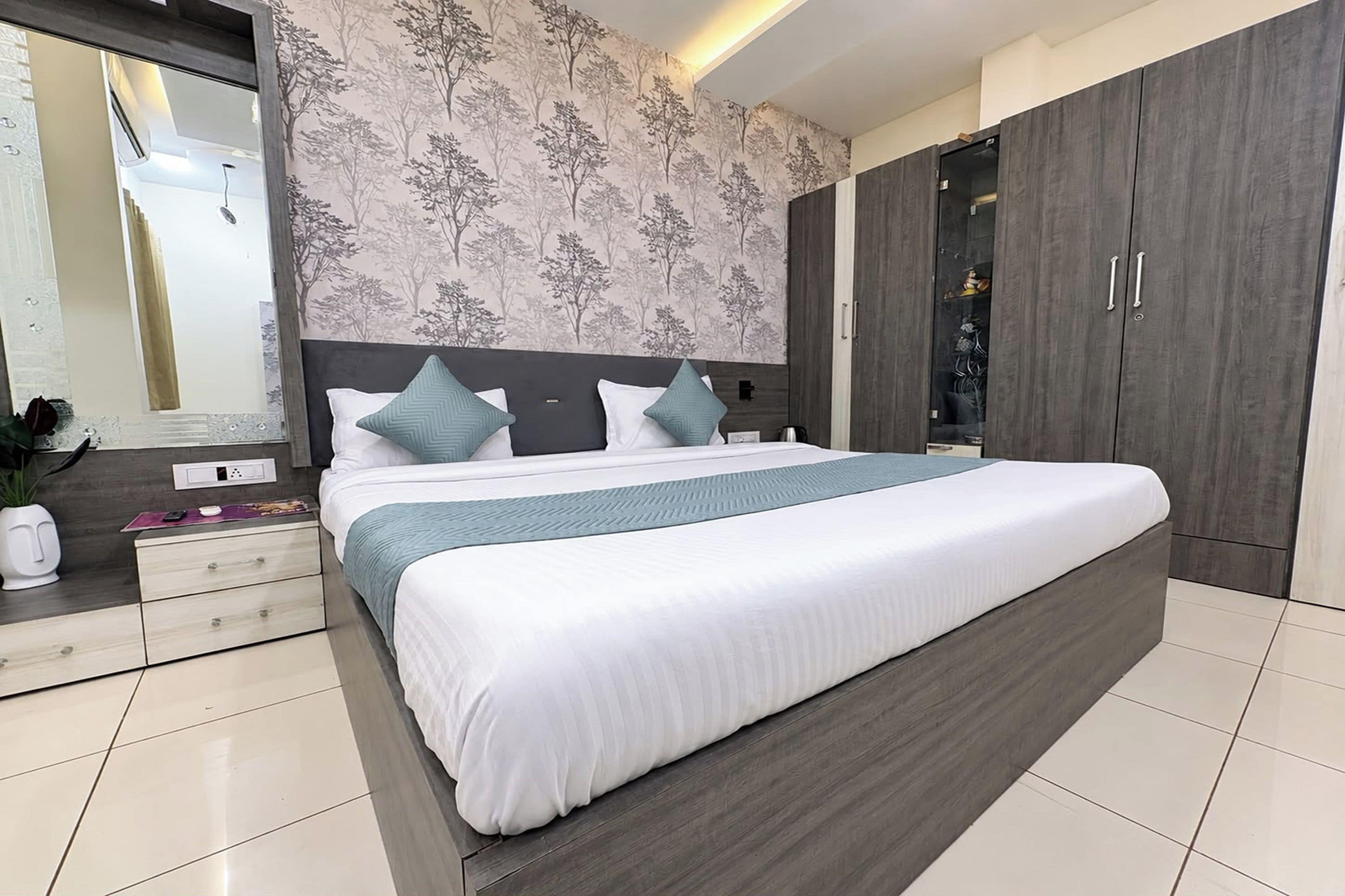 A modern bedroom with a large bed, a nightstand, a dresser, and a wardrobe.