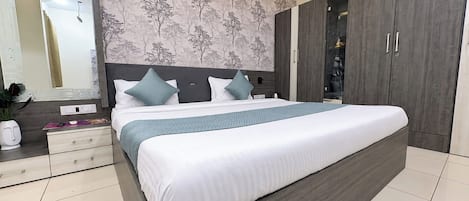 A modern bedroom with a large bed, a nightstand, a dresser, and a wardrobe.