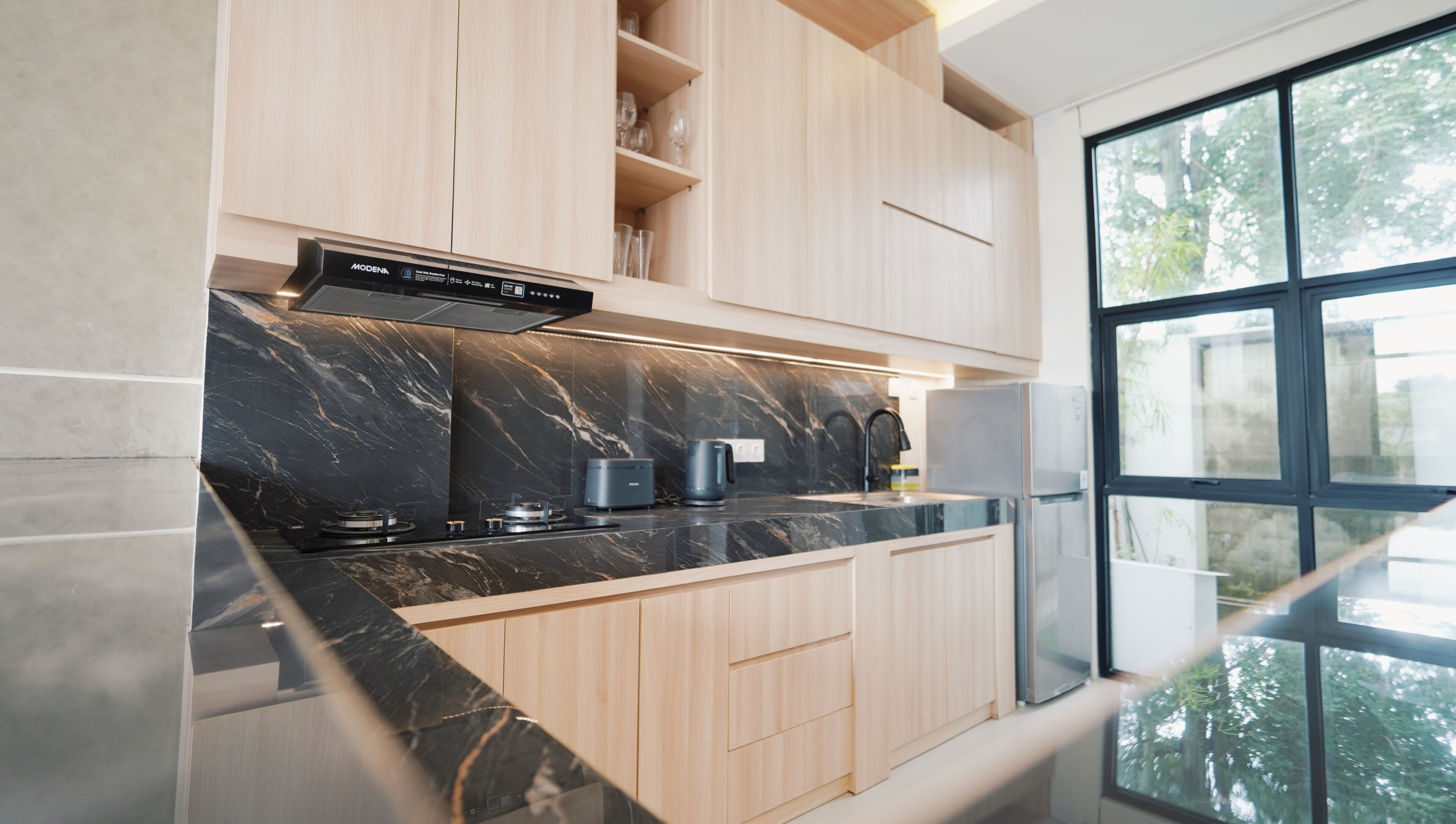 Una cucina moderna con un piano di lavoro in marmo nero, mobili in legno e un forno integrato.