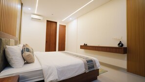 A modern bedroom with a bed, bedside tables, a wooden wardrobe, and a wall-mounted shelf. - SLOKAYANA VILLAS (Pecatu)