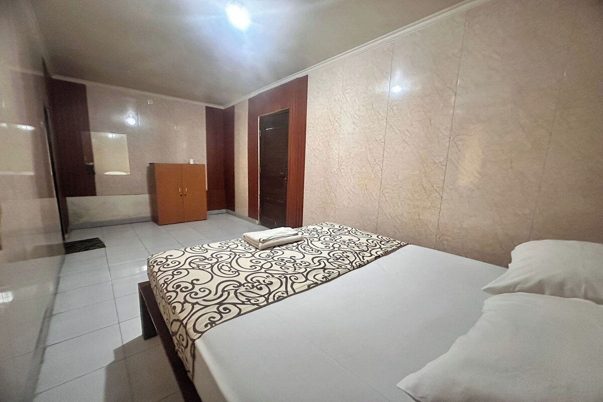 A hotel room with a bed, a wardrobe, and a mirror.