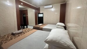 A hotel room with two beds, a mirror, an air conditioning unit, and a patterned rug. - BB Homestay Two (Pecatu)