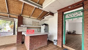 An office area with a brick counter, a whiteboard, and a sign indicating office hours. - BB Homestay Two (Pecatu)