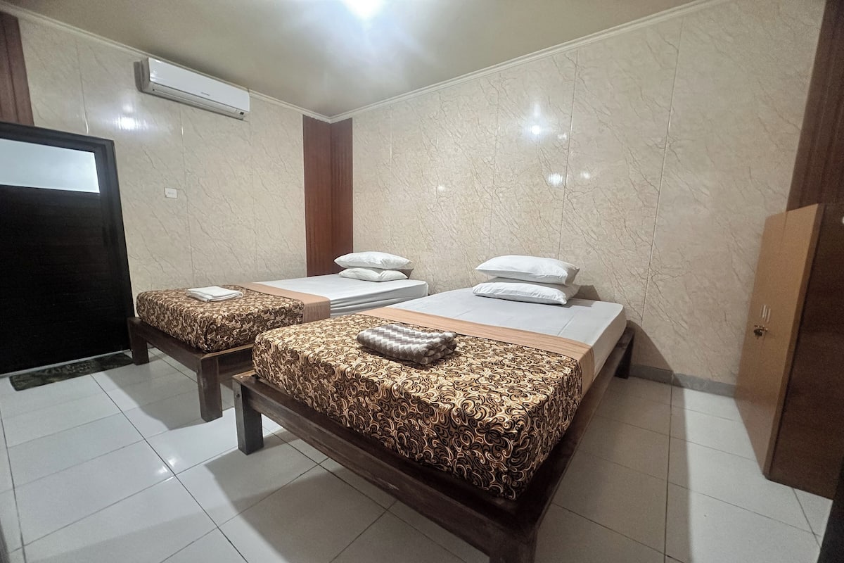A hotel room with two beds, a TV, and a wardrobe.