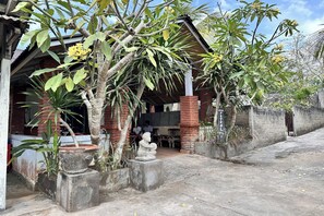 Un edificio tradicional con un porche cubierto, pilares de ladrillo y plantas en macetas.